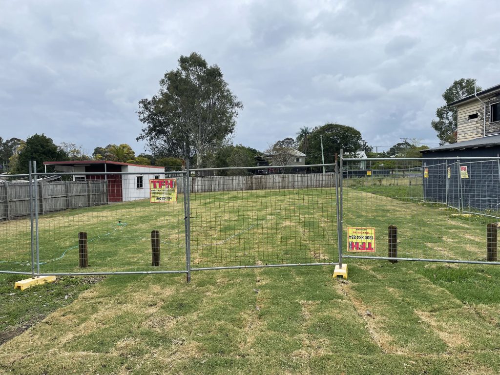 Fencing around a vacant lot with newly laid turf